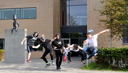 Billedet viser nogle store elever uden for indgangen på afdeling Fussingsvej, der alle hopper i luften og har det sjovt