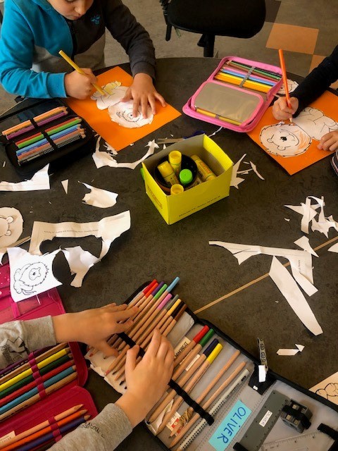 Billedet viser nogle børn, der klipper løver ud af papir og farvelægger dem