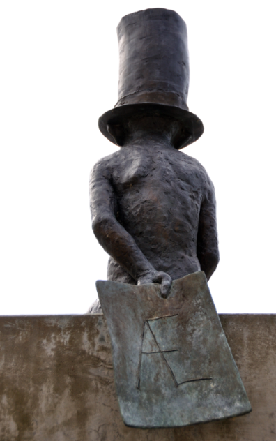 Billedet viser bagsiden af skulpturen, La Vida fra 2012 af Michael Kvium, lavet i bronze, som holder et stykke papir bag ryggen med bogstaven Æ