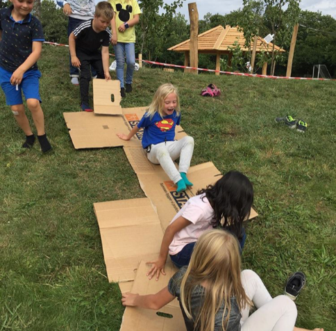 Billedet viser børn i SFO'en, der har det sjovt og glider ned ad en bakke på papkasser ved afdeling Lindvigsvej